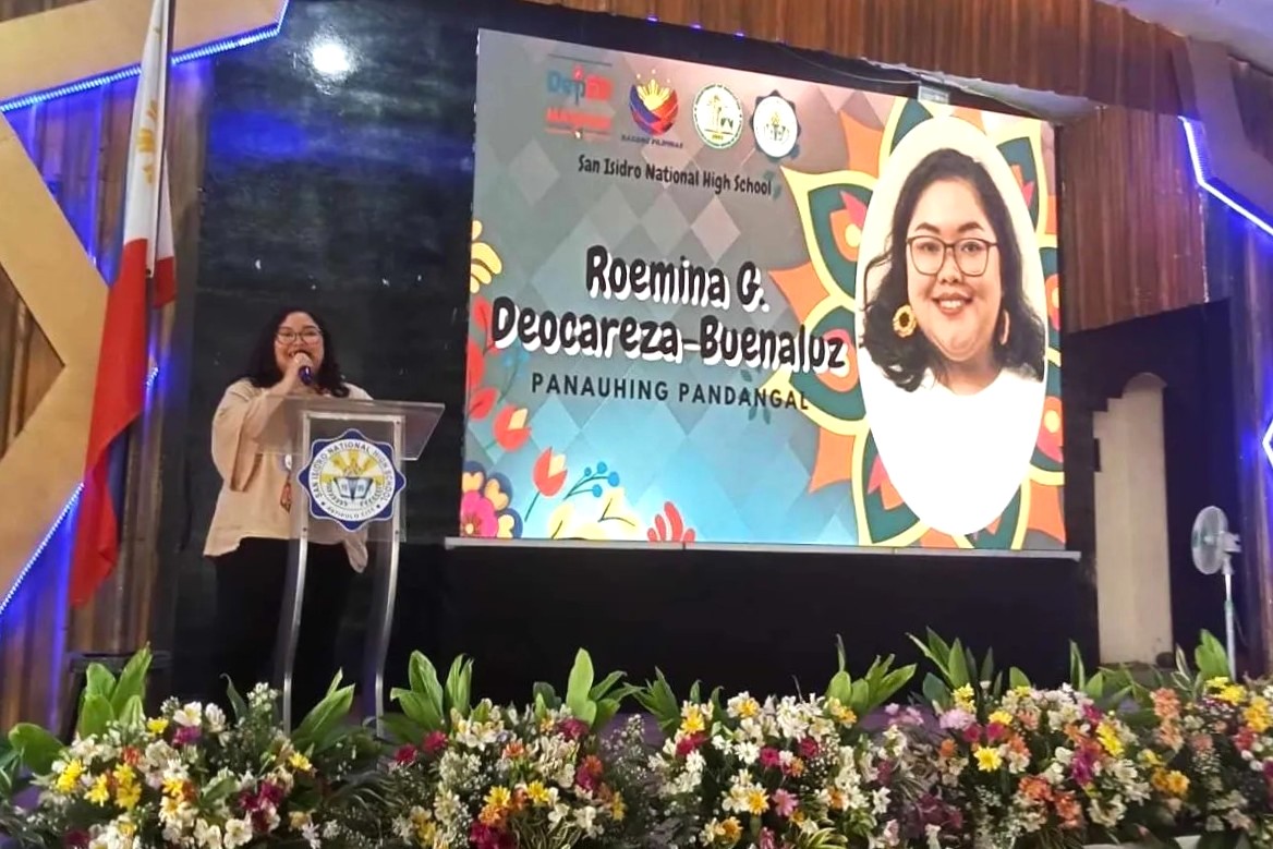 woman speaking on the stage of her high school